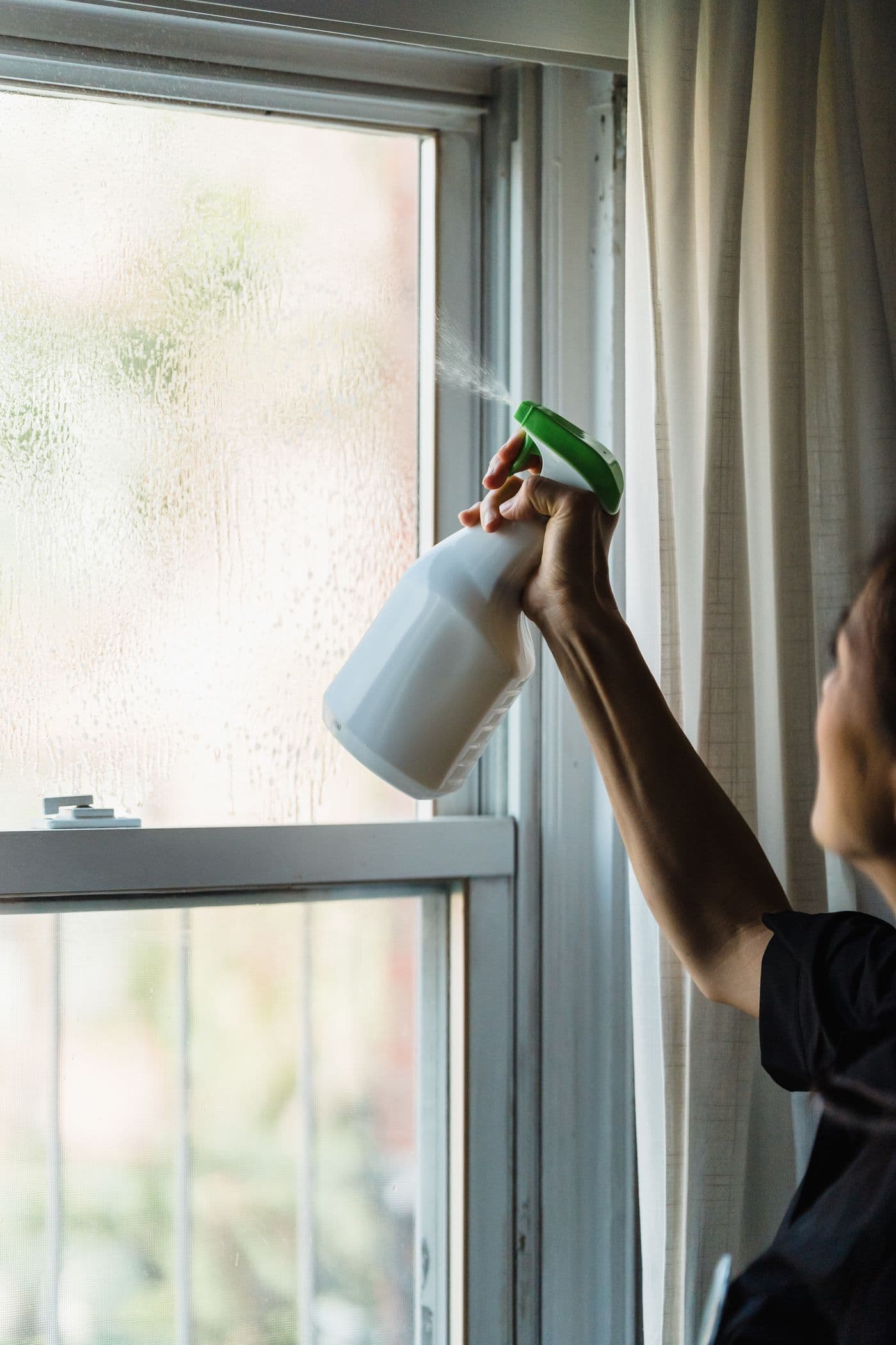Vaporisation d'un produit à vitres sur une fenêtre à contre-jour